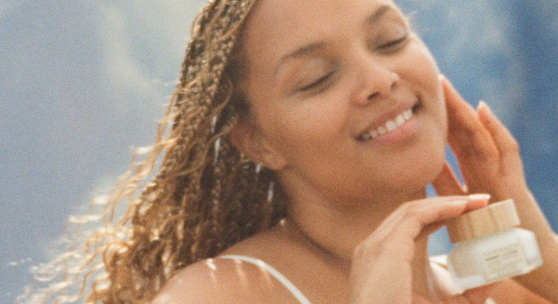 Woman applying face lotion with a blue sky background