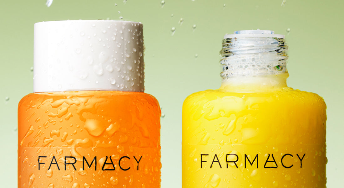 Two Farmacy skincare bottles, one orange and one yellow, on a light green background.