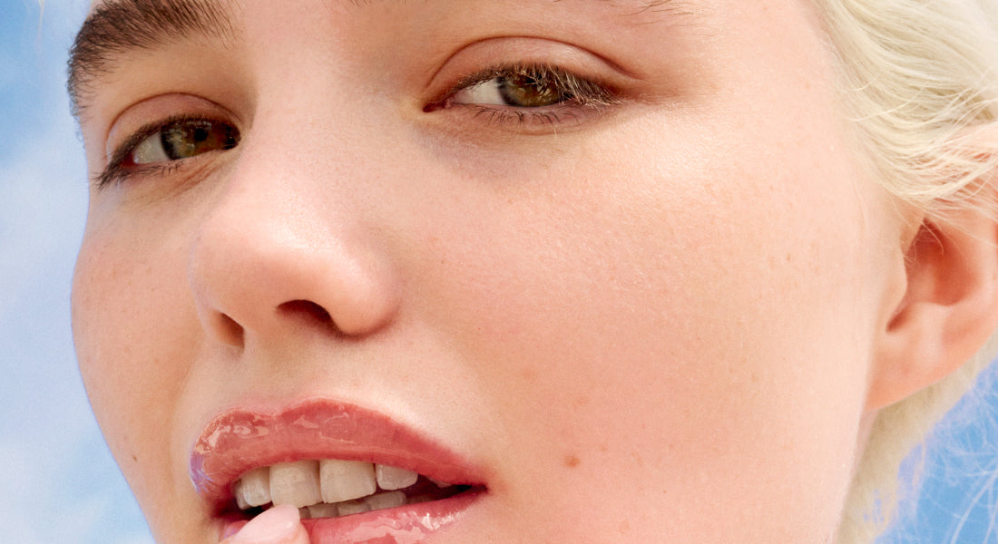 Close-up of a person with blonde hair and blue eyes against a light blue background