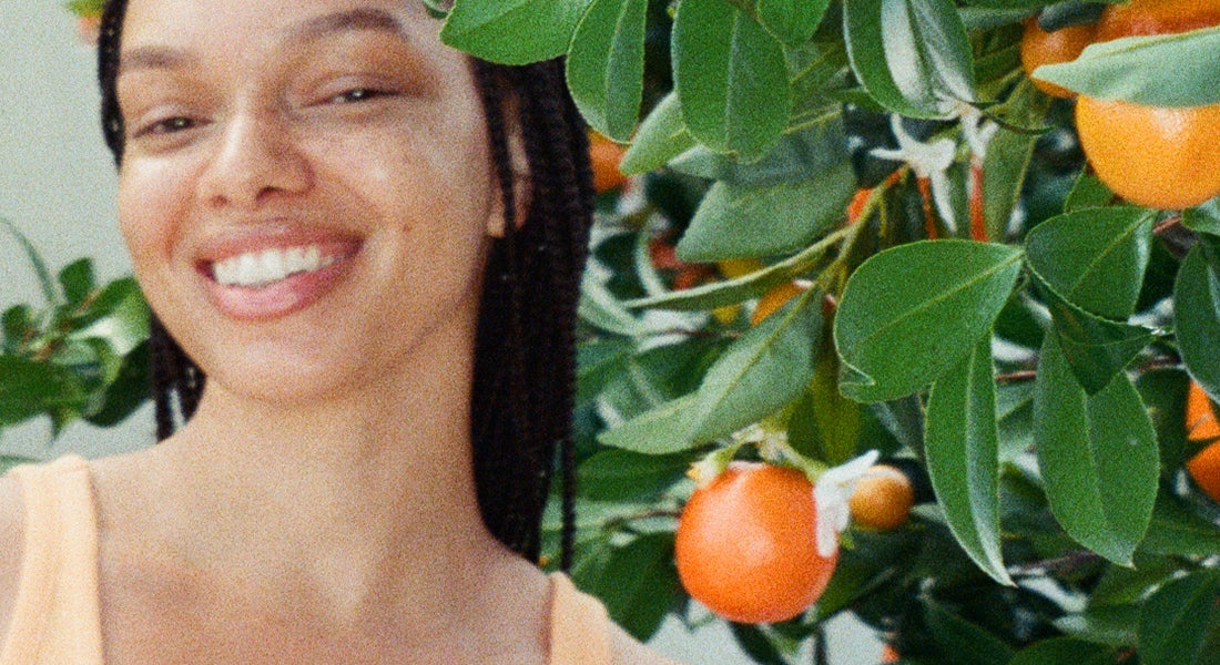 Woman standing next to a tree with orange fruits