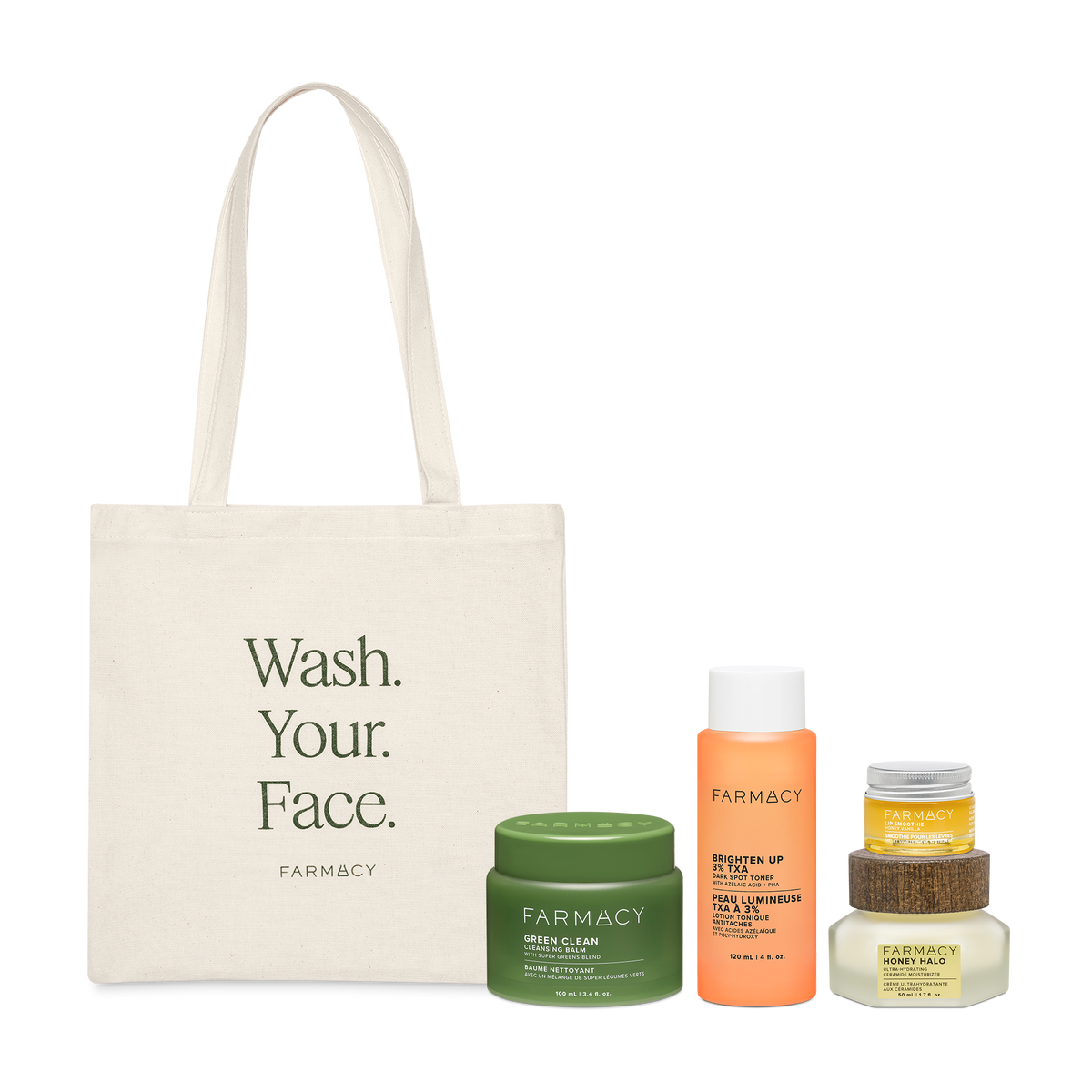 Farmacy Ultimate Best Seller Kit featuring Green Clean 100 mL, Brighten Up TXA Toner 120 mL, Honey Halo Moisturizer 50 mL, Honey Vanilla Lip Smoothie 10 g, and an off-white tote bag with the words ''WASH YOUR FACE'' written in dark green and the FARMACY logo, on a white background.