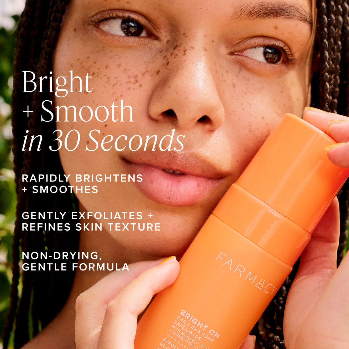 Woman holding a bottle of Farmacy Beauty Bright On Foam Exfoliator with text about its benefits